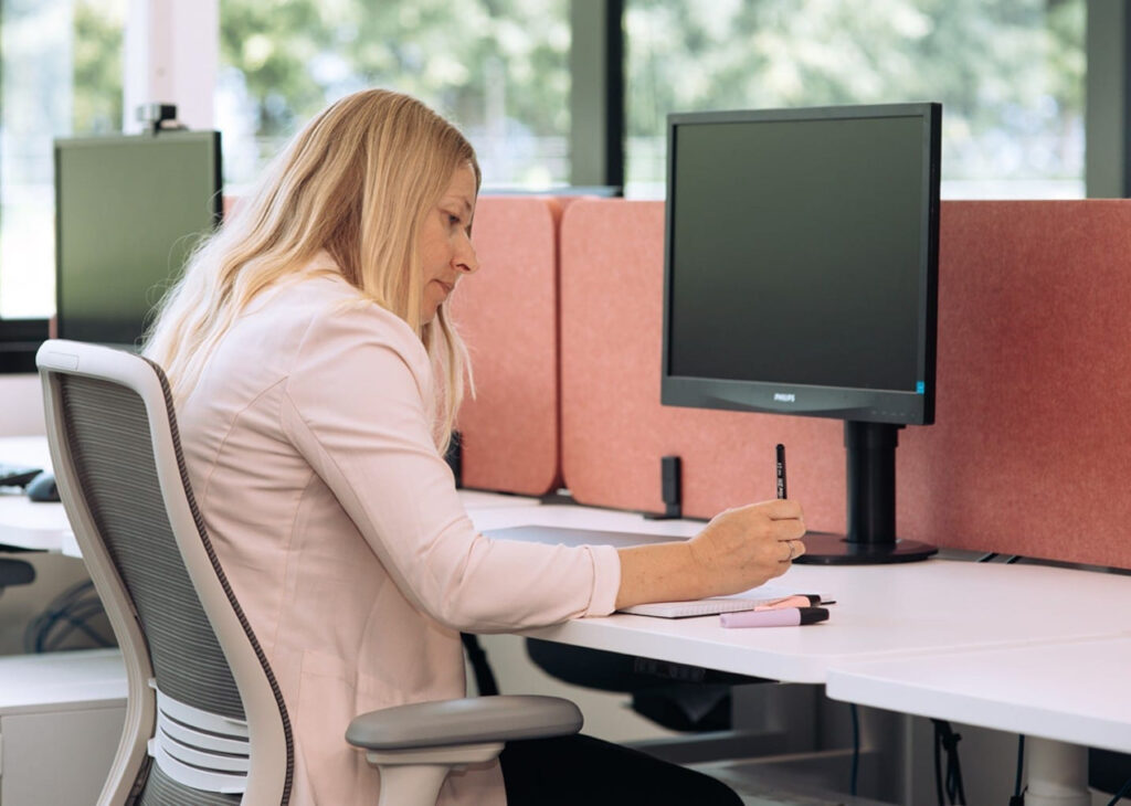 Employee working at a workstation with acoustic screening in the ACCO Auckland office.